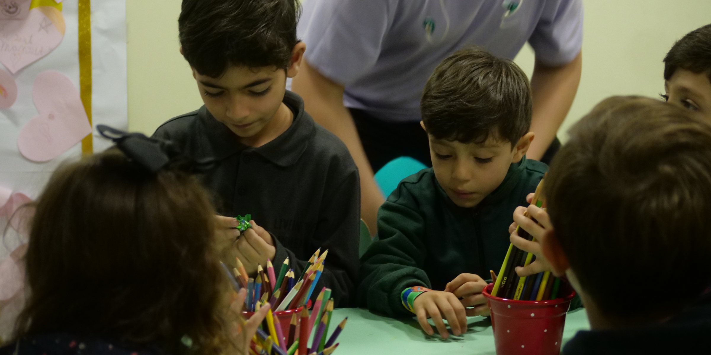 Crianças do C3 Kids numa atividade com lápis de cor, acompanhadas pela equipe.