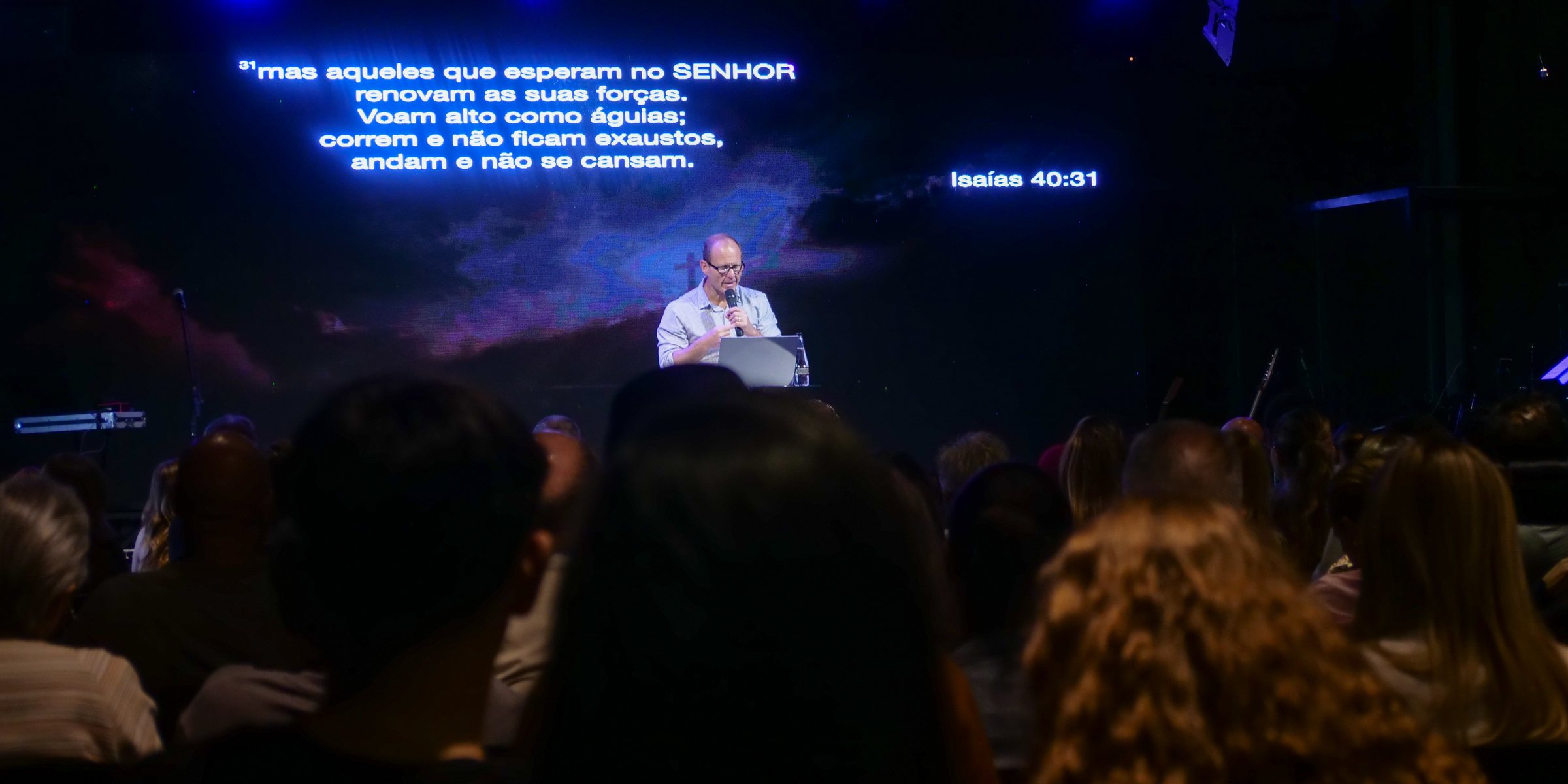 Pregação no culto da C3 Curitiba, com o versículo de Isaías 40:31 projetado no telão.
